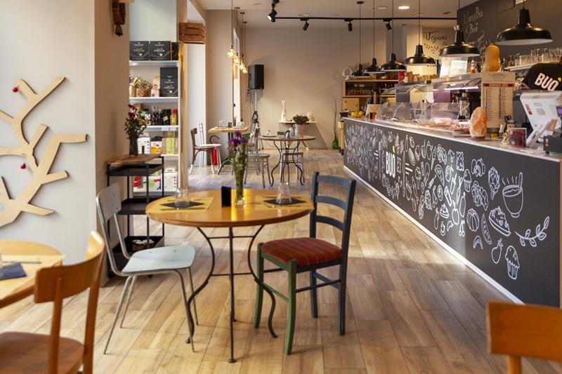Sala di Buò con bancone nero decorato da disegni di cibo a gessetto, tavolini rotondi in ferro e pavimento in legno